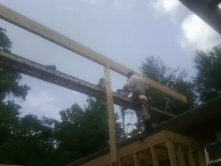 Carpenter setting a ridge beam over a new addition frame — Ice Dam Removal by Roofing Brothers in Chevy Chase