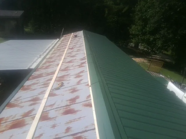 Old rusted panels beside newly installed green metal roofing — Wind Damage Roof Repair by Roofing Brothers in Chevy Chase