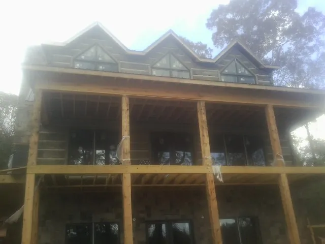 Dormers and porch framing on a large log home under construction — Roof Coating work by our crew in Chevy Chase