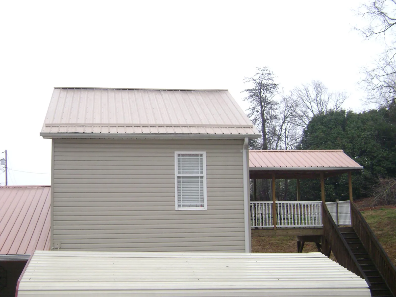 Tan metal roofs on a two story addition and attached porch, from a Roof Replacement job in Chevy Chase