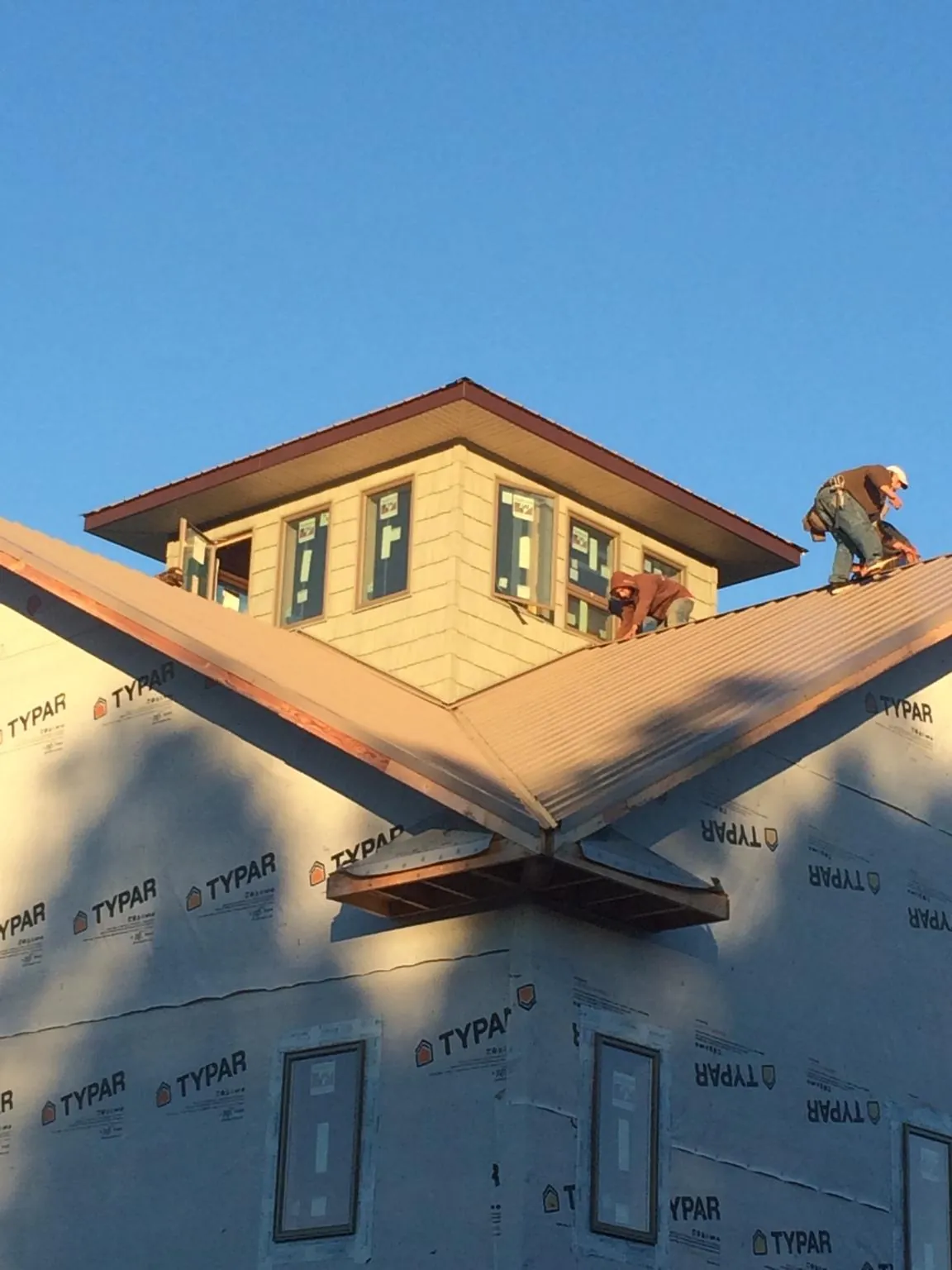 Roofers working around a rooftop cupola on a new metal roof at sunset — Roof Waterproofing in Chevy Chase by Roofing Brothers
